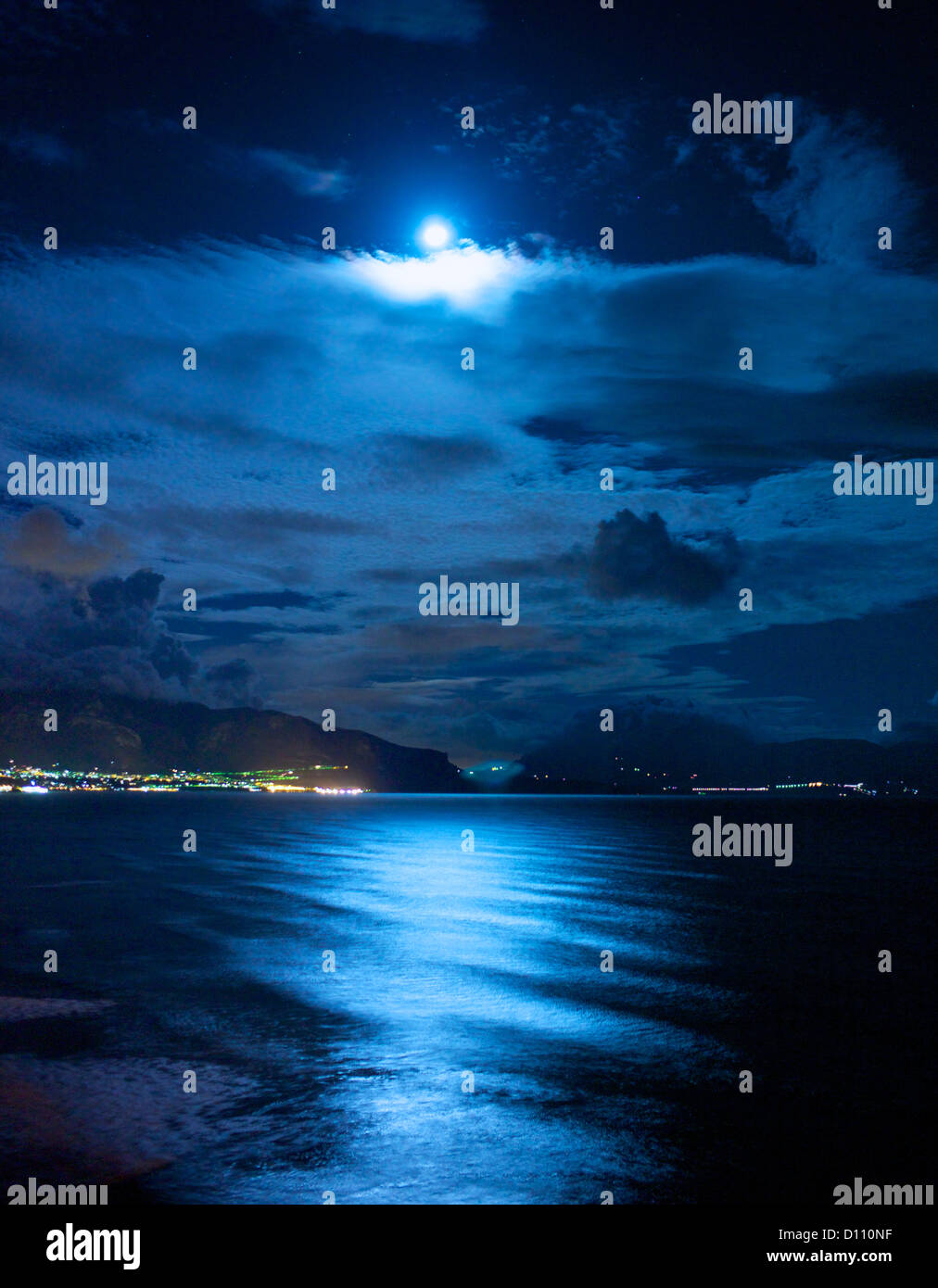 Die Stadt in der Ferne beleuchtet neben dem Meer in der Nacht Stockfoto