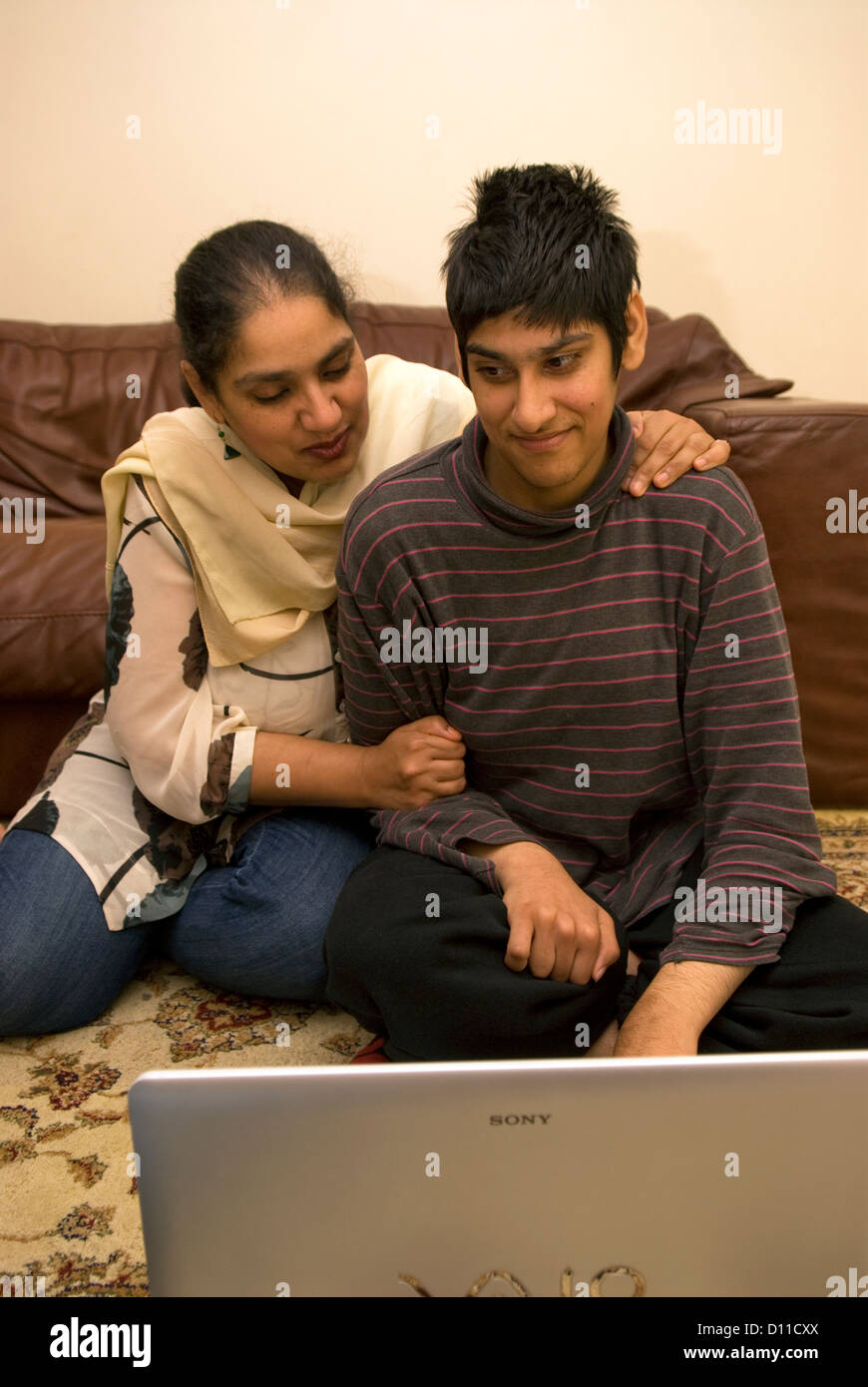 Mutter, die kümmert sich um ihre 24-jährige Tochter mit Zerebralparese spielen auf Laptop, London, UK. Bild-Modell veröffentlicht. Stockfoto