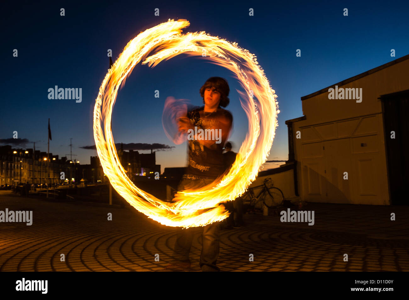 Ein junger Mann Feuer Poi Jonglage und andere Fähigkeiten, Dämmerung,  abends. Aberystwyth Küste Wales UK Stockfotografie - Alamy