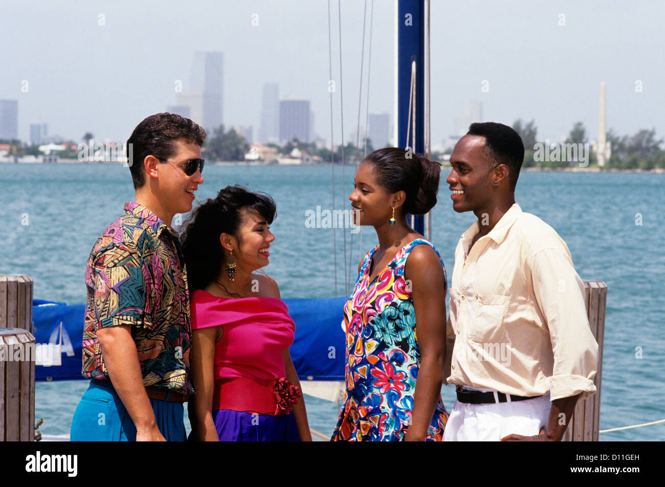 DER 1990ER JAHRE ZWEI PAARE KAUKASISCHEN & AFROAMERIKANISCHEN AM DOCK VON SEGELBOOT SKYLINE VON MIAMI Stockfoto