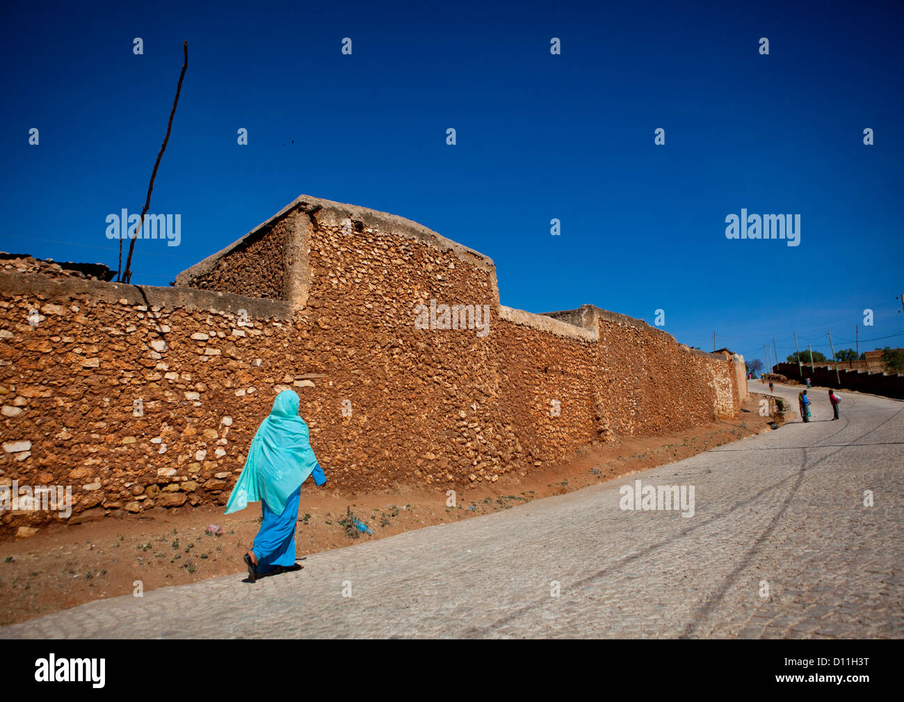 Blau gekleidete Frau vorbei an den alten Mauern, Harar, Äthiopien Stockfoto