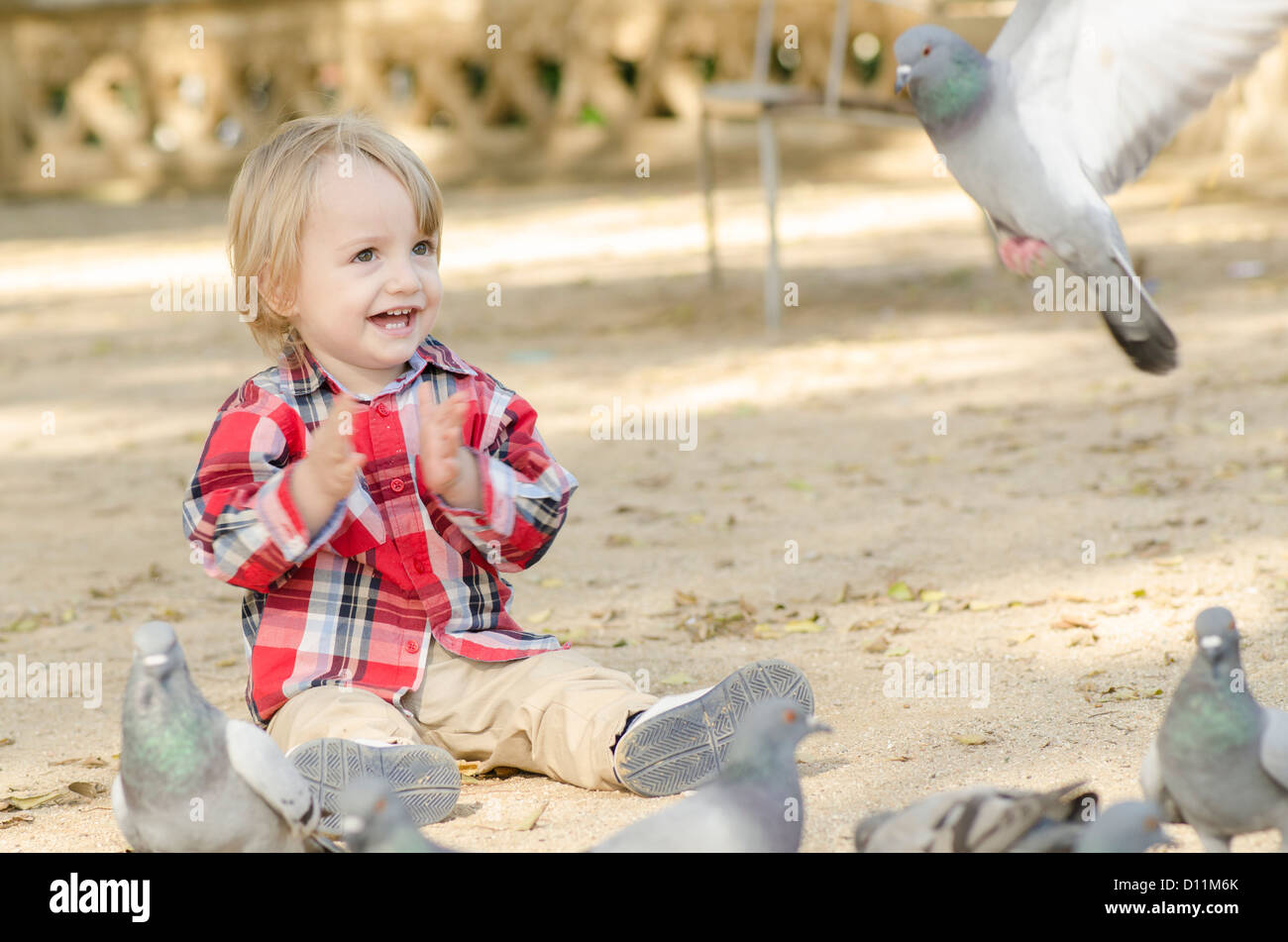 Ein Baby Lächeln auf den Lippen umgeben von Tauben fliegen herum Stockfoto