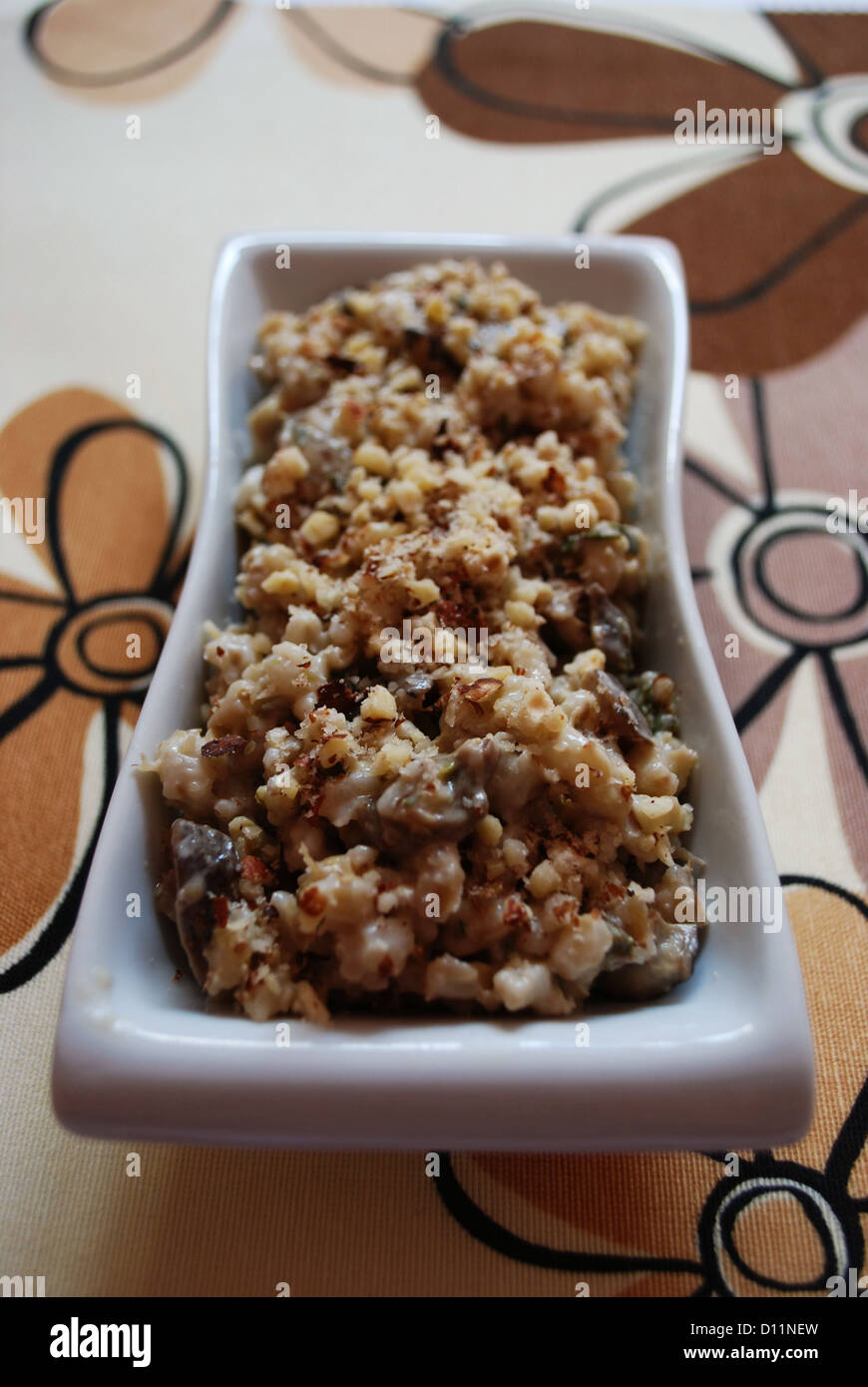 Herbstliche vegetarische Rezept Gerste mit Pilzen zubereitet und serviert mit gerösteten Haselnüssen Stockfoto