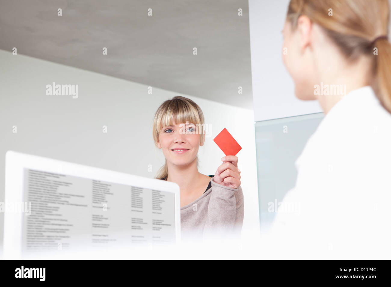 Deutschland, Patienten geben Versicherungskarte an Rezeption in Zahnarztpraxis Stockfoto