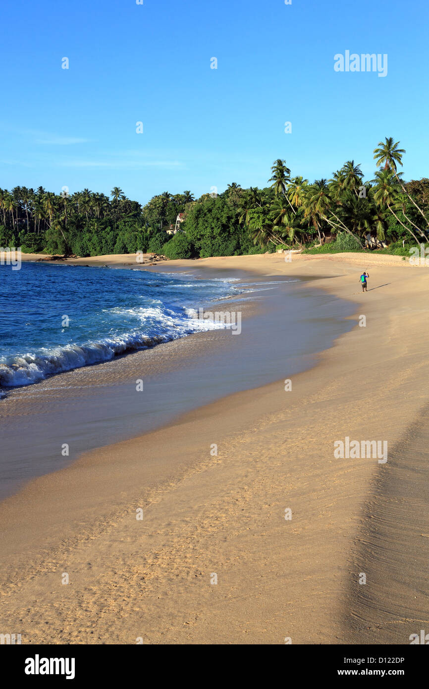 Ein einsamer Mann am frühen Morgen Angeln auf einem schönen weißen Sandstrand in Tangalle auf der Südküste Sri Lankas Stockfoto