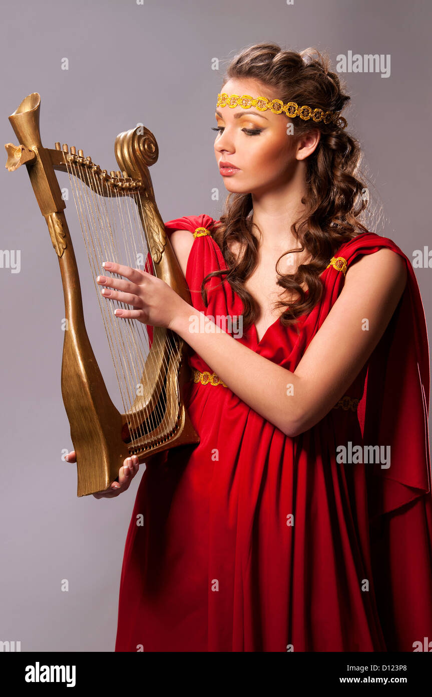 niedliche Mädchen in eine rote Tunika mit einer Harfe Stockfoto