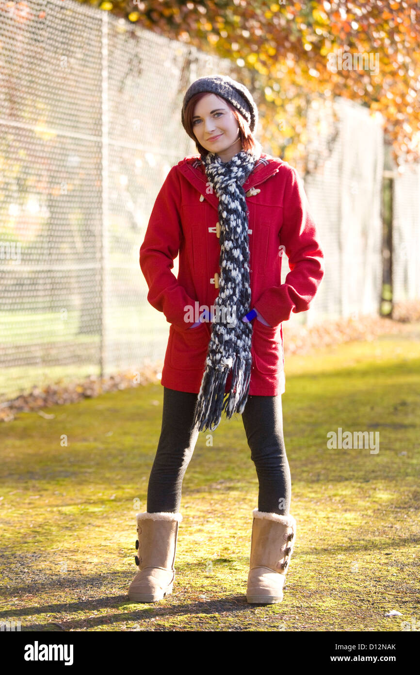 Junge Frau trägt einen roten Mantel in einem Park in Schottland. Stockfoto