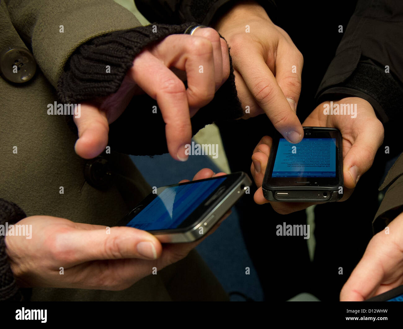 Die Abbildung zeigt zwei Menschen, die mit ihren Handys zu schreiben und senden Sie instant Messages in München, 3. Dezember 2012. Foto: Peter Kneffel Stockfoto