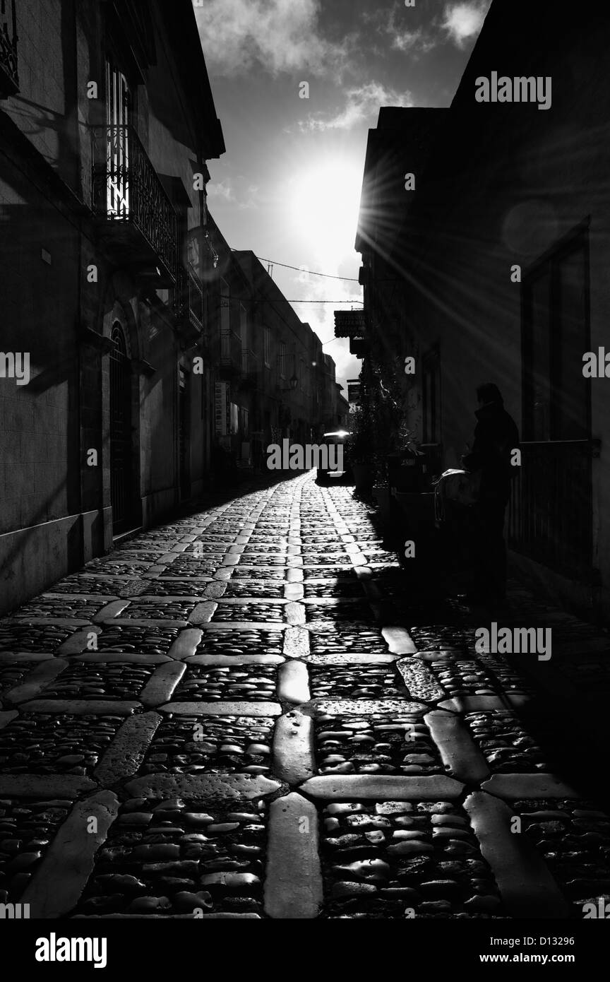 Schmale gepflasterte Straße zwischen Gebäuden in Sizilien in der Abenddämmerung Stockfoto