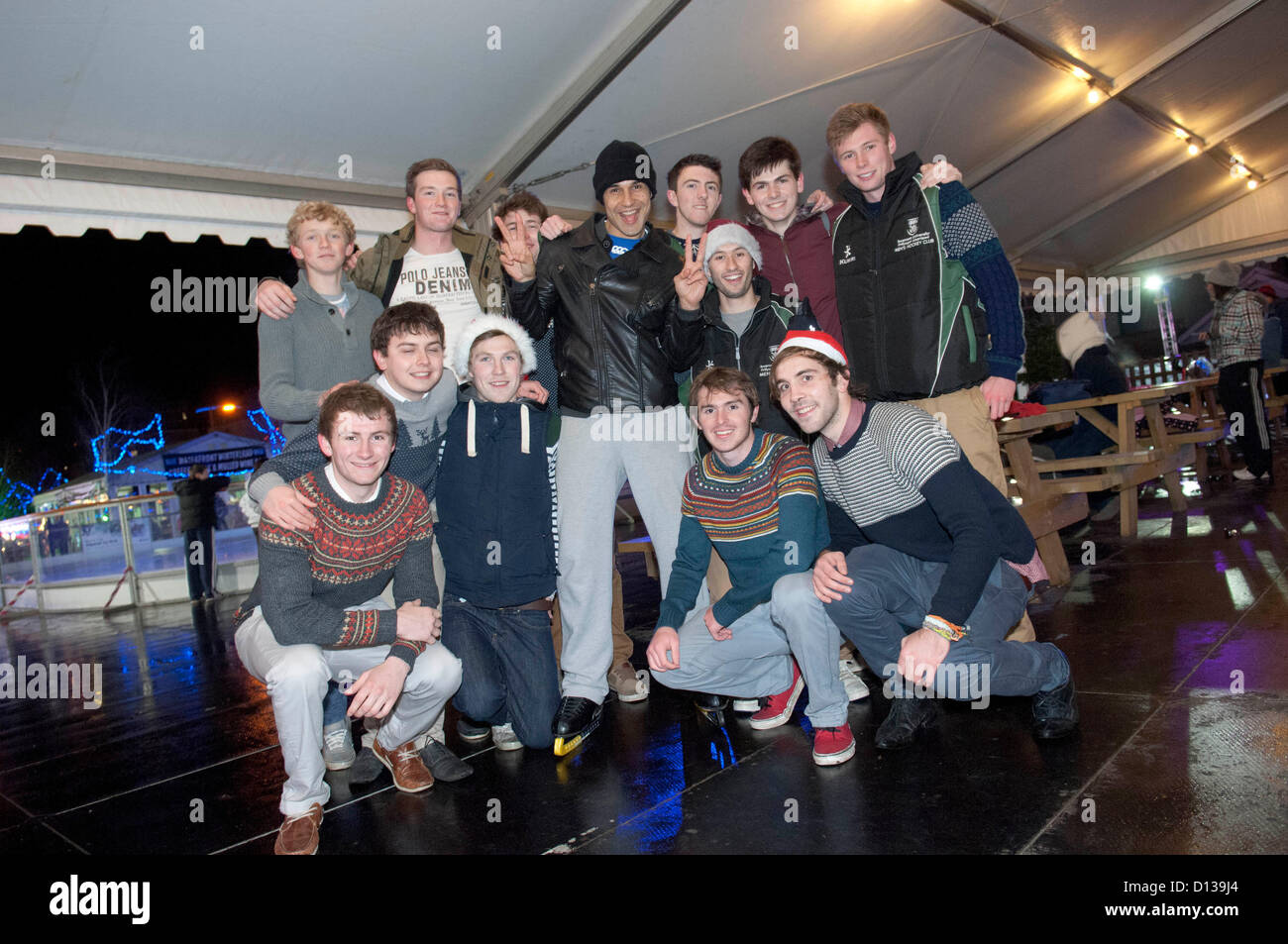 Chico Slimani Besuch der Eisbahn an der Waterfront Winterland neben der Waterfront Museum in Swansea. Chico war eine Pause von Proben für die Panto - Cinderella, am Grand Theatre in Swansea nächste Woche beginnt. Er ist mit den Mitgliedern der Swansea University Hockey Team abgebildet. Stockfoto