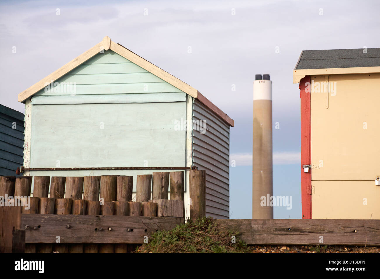 Strand Hütten mit Blick auf Fawley Power Station Tower dazwischen bei Calshot, Hampshire im November Stockfoto