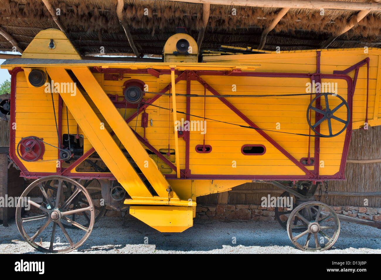 Antike gelben Bauernhof wegwerfen Maschine unter Stroh vergossen Stockfoto