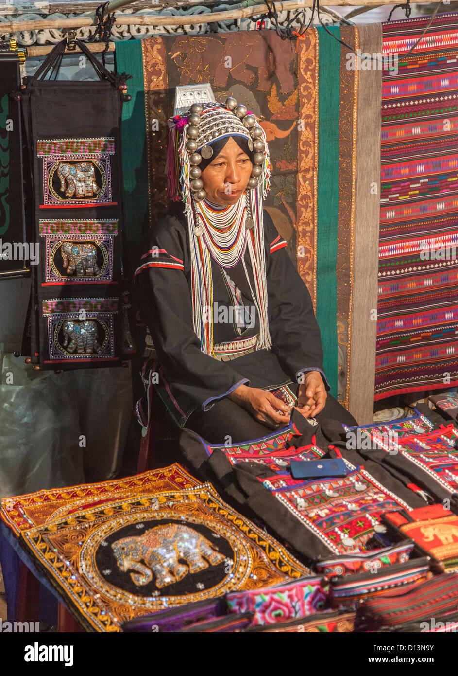 Stall am Nachtmarkt in Chiang Rai, Nordthailand mit Frau in typischen traditionellen Hill Tribe Kostüm und Kopfschmuck Stockfoto