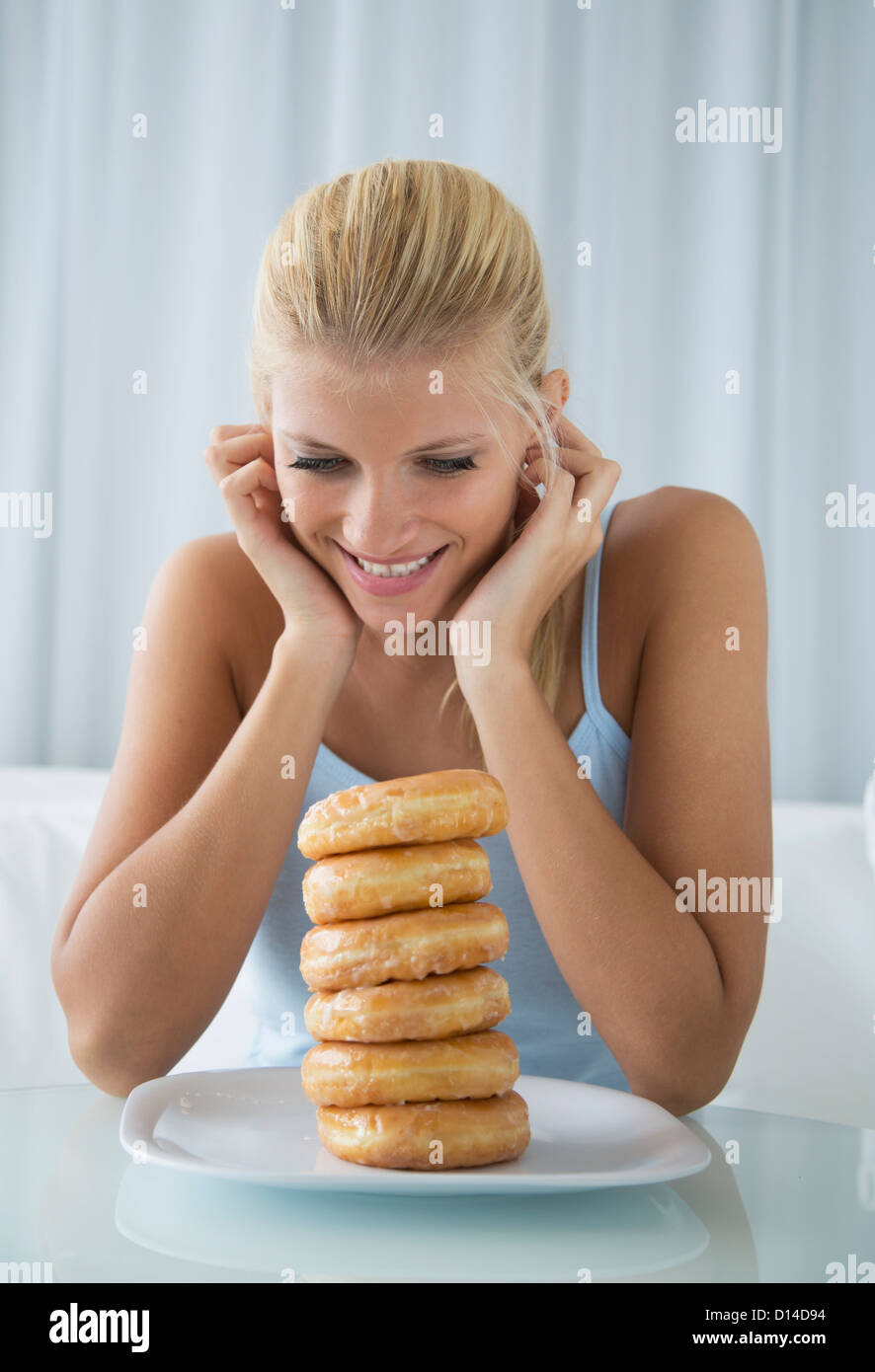 Frau bewundernde Stapel Donuts Stockfoto