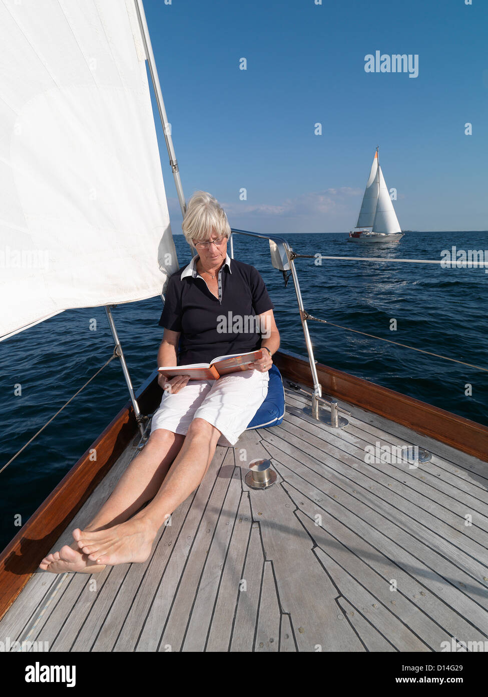 Ältere Frau liest auf Segelboot Stockfoto