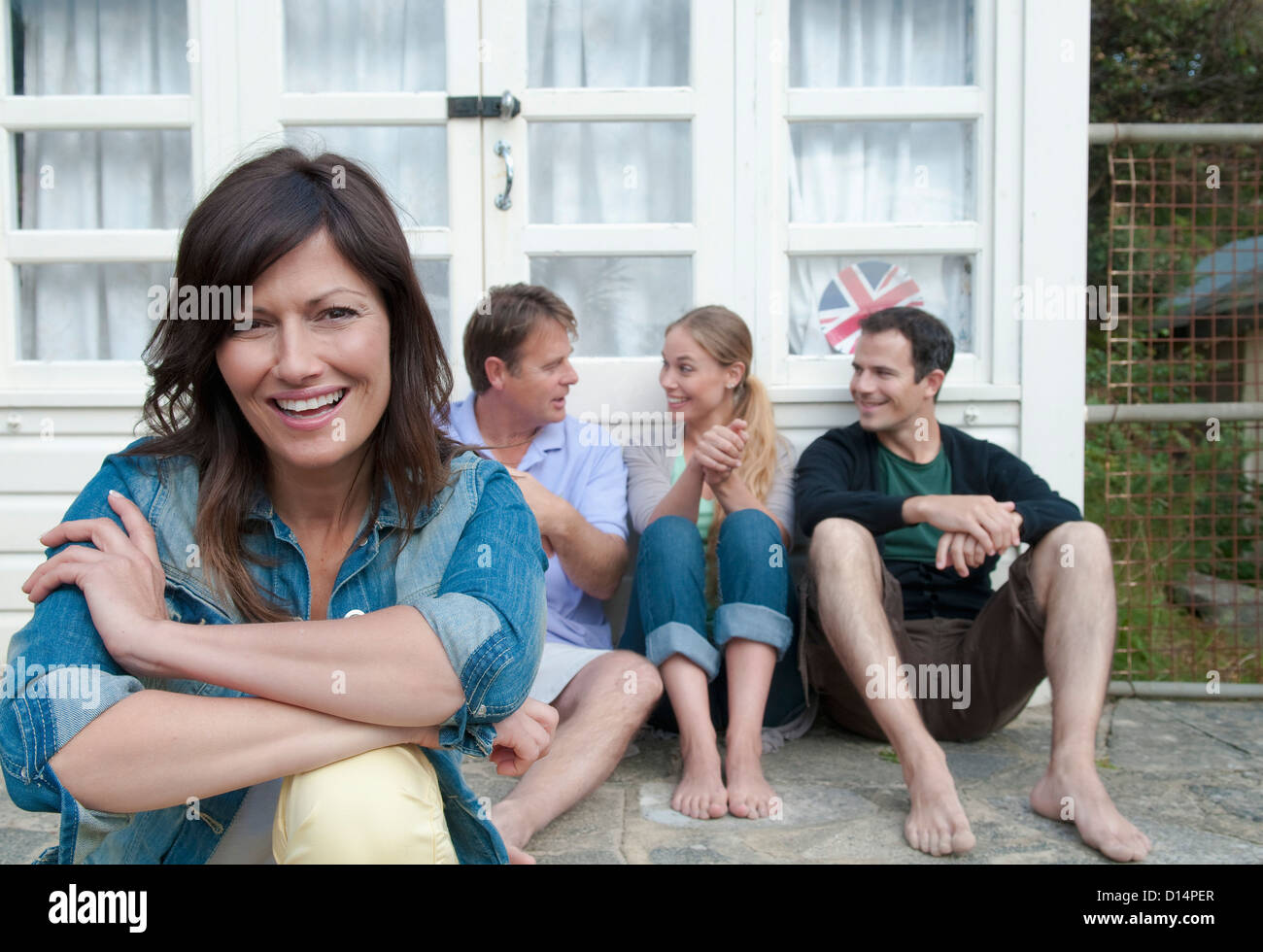Frau sitzt mit Familie vor Haus Stockfoto