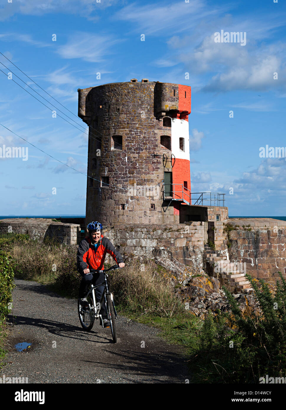 Frau Radfahrer am Archirondel Turm, le Havre de Fer, Ostküste Jersey, Kanalinseln, Großbritannien Stockfoto