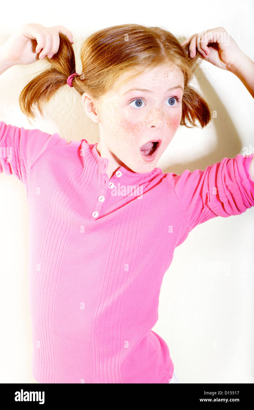 Junges Mädchen mit Sommersprossen und rote Haare In Zöpfen posiert im Studio. Stockfoto