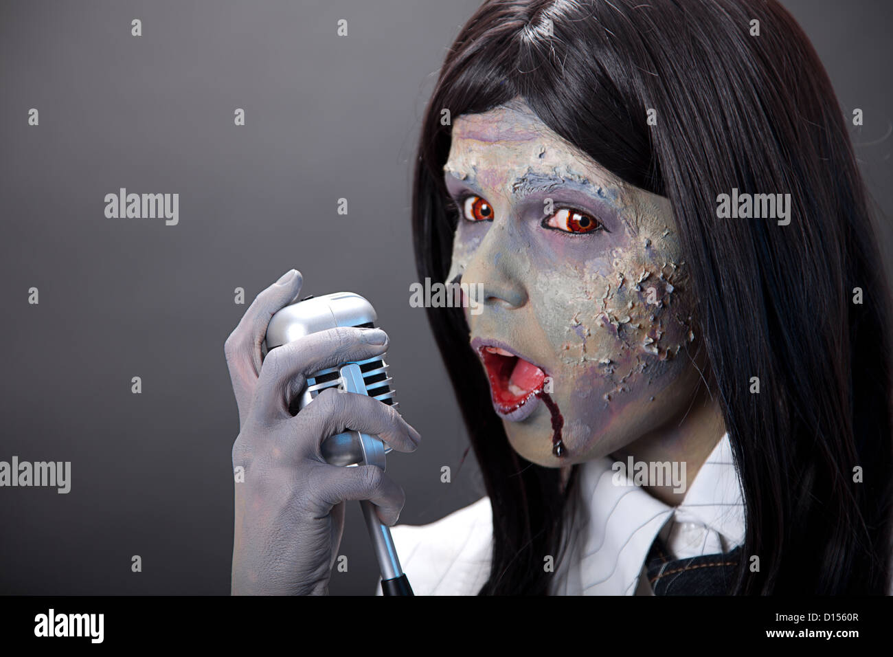 Niedliche Zombie Mädchen Sängerin mit Retro-Mikrofon, Studio gedreht Stockfoto