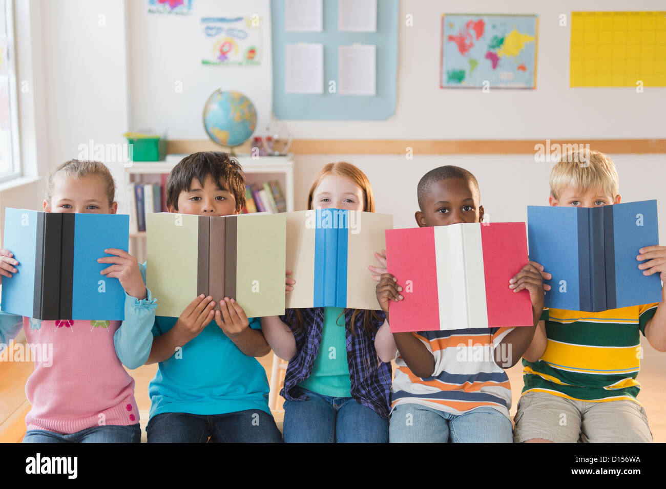 USA, New Jersey, Jersey City, Schulkinder (8-9) sitzen in Reihe mit offenen Bücher Stockfoto