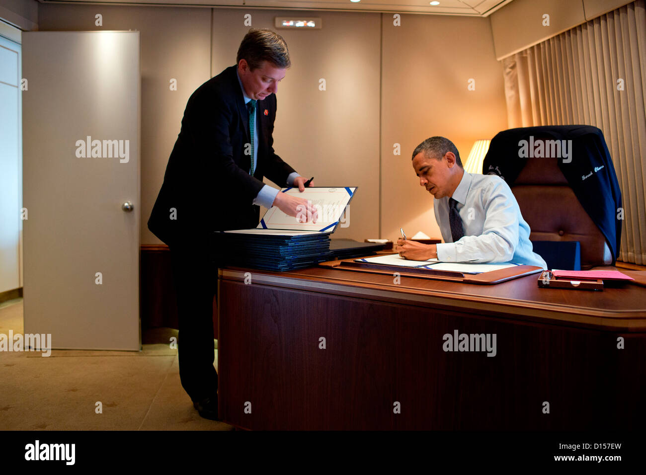 US-Präsident Barack Obama unterzeichnet Rechnungen an Bord der Air Force One während des Fluges nach Cleveland, Ohio, 5. Oktober 2012. Der Präsident ist Personal Secretary Doug Kramer. Stockfoto
