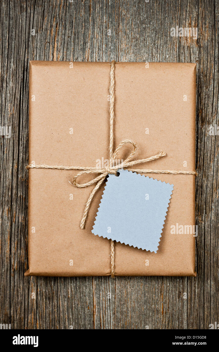 Geschenkverpackung und Karte in braun Papierverpackung gebunden mit Schnur an rustikalen Holz Hintergrund Stockfoto