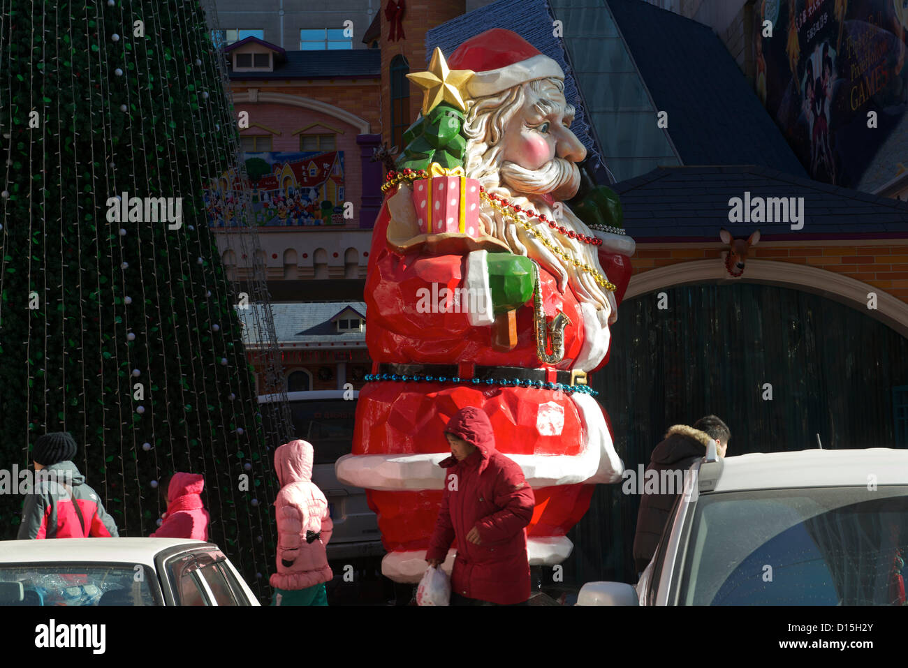 Chinesische Fußgänger Vorbeigehen einen riesigen Weihnachtsmann und Weihnachtsbaum außerhalb eine Warenbörse am 8. Dezember 2012 in Peking, China. Stockfoto