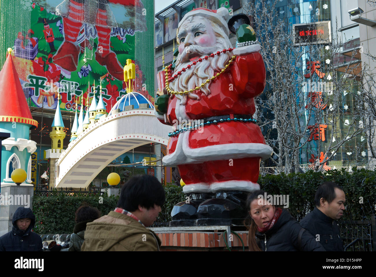 Chinesische Fußgänger Vorbeigehen einen riesigen Weihnachtsmann außerhalb eine Warenbörse am 8. Dezember 2012 in Peking, China. Stockfoto