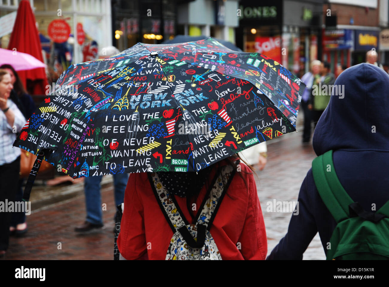 Zuflucht vor dem Regen mit bunten Regenschirm (Canterbury UK) Stockfoto