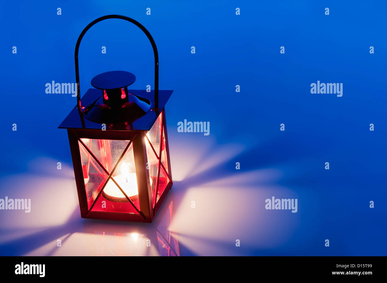 Dekorative rote Laterne Licht mit intensiv leuchtenden Flamme brennt in der Nähe von blauen Glas Tisch mit Textfreiraum. Stockfoto