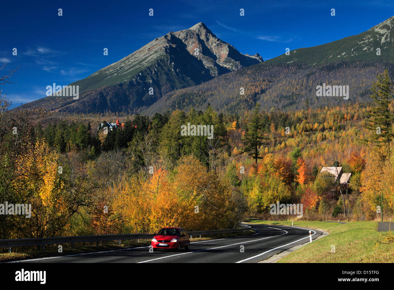Rotes Auto fahren entlang der Straße in Tatranska Lomnica in der Tatra-Region der Slowakei Stockfoto