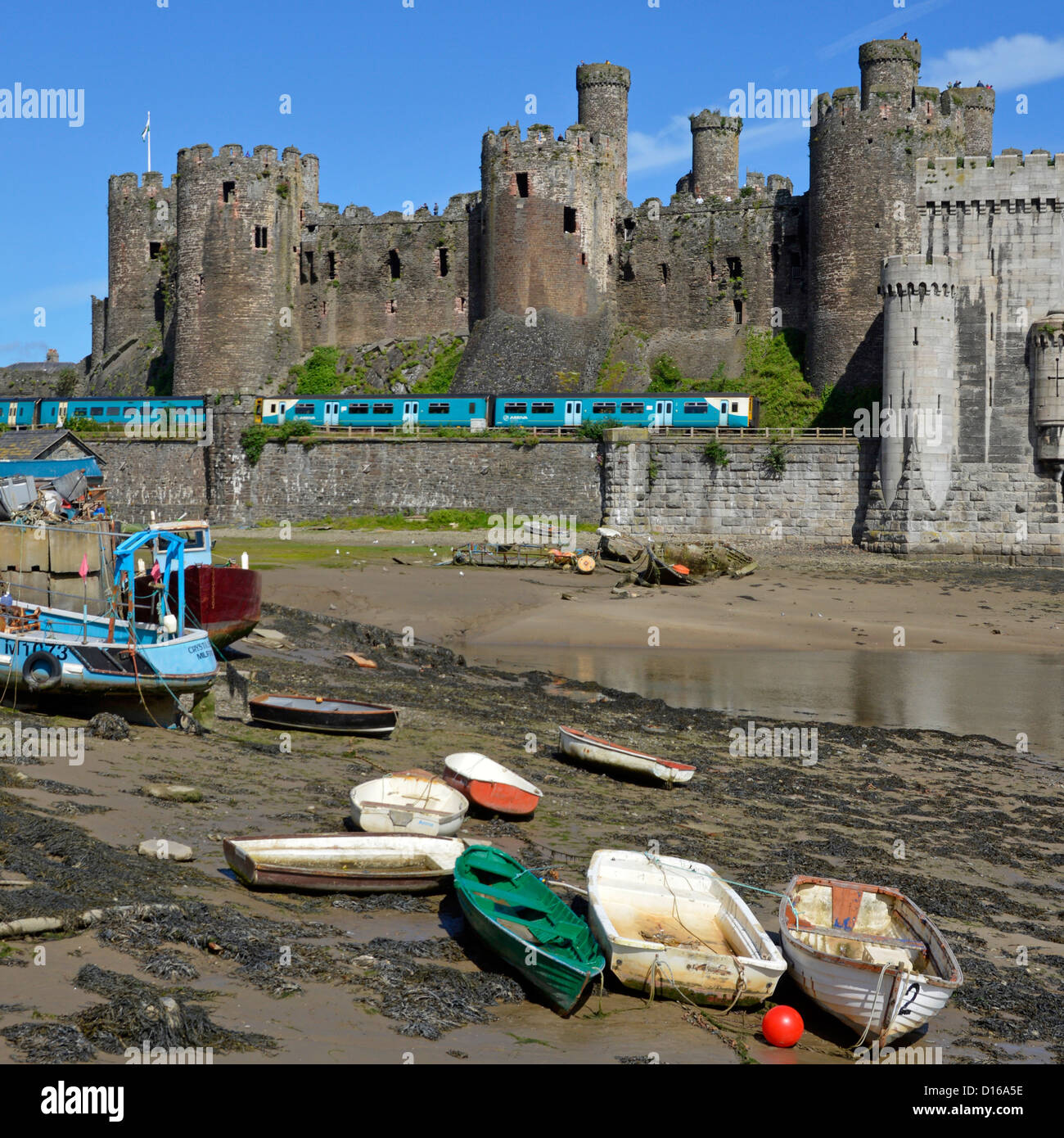 Bahnlinie & historischer Conwy Castle Arriva Zug verlässt Robert Stephenson Eisenbahnbrücke über River Conwy kleine Boote auf Vorschiff Clwyd North Wales UK Stockfoto