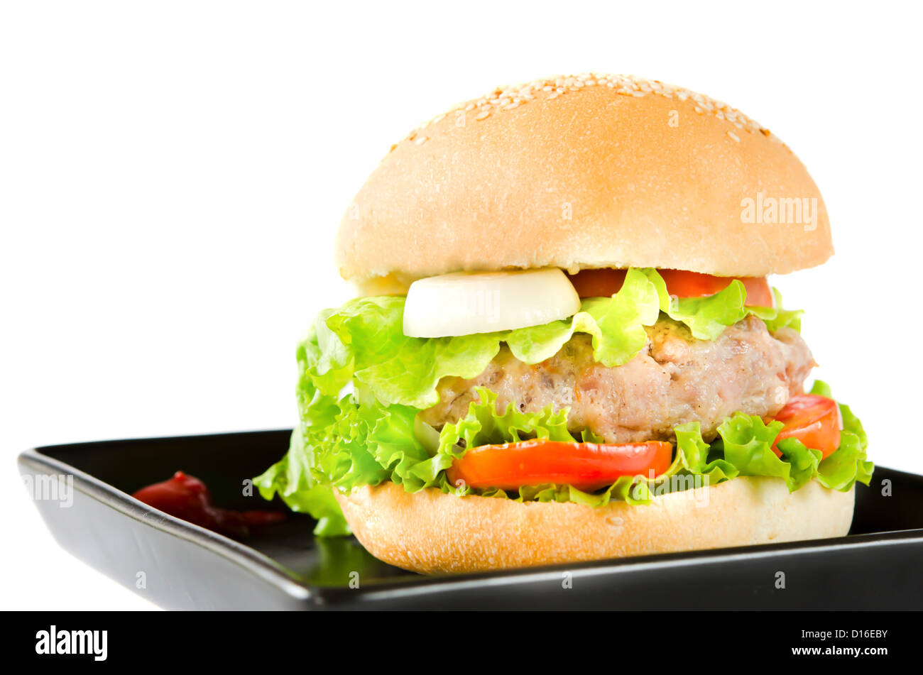 großen Hamburger mit Tomatensauce auf schwarzem Teller Stockfoto