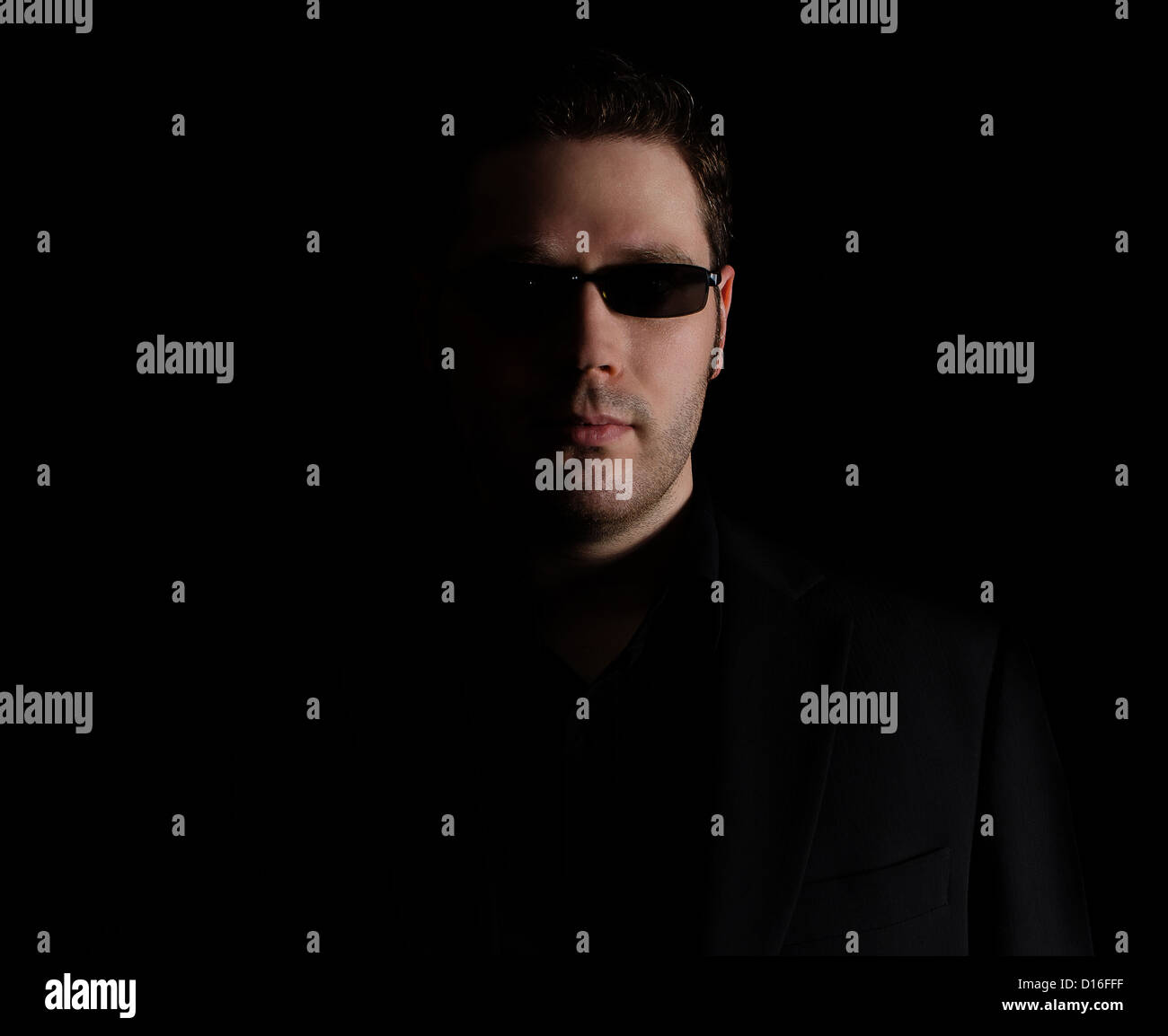 Portrait der Mann im schwarzen Anzug auf schwarzem Hintergrund Stockfoto