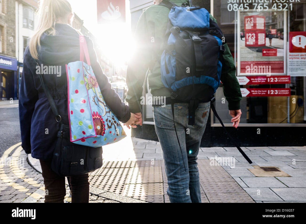 Rückansicht eines jungen Paares gehen Hand in Hand einher auf eine Filiale der Santander Bank, UK Stockfoto