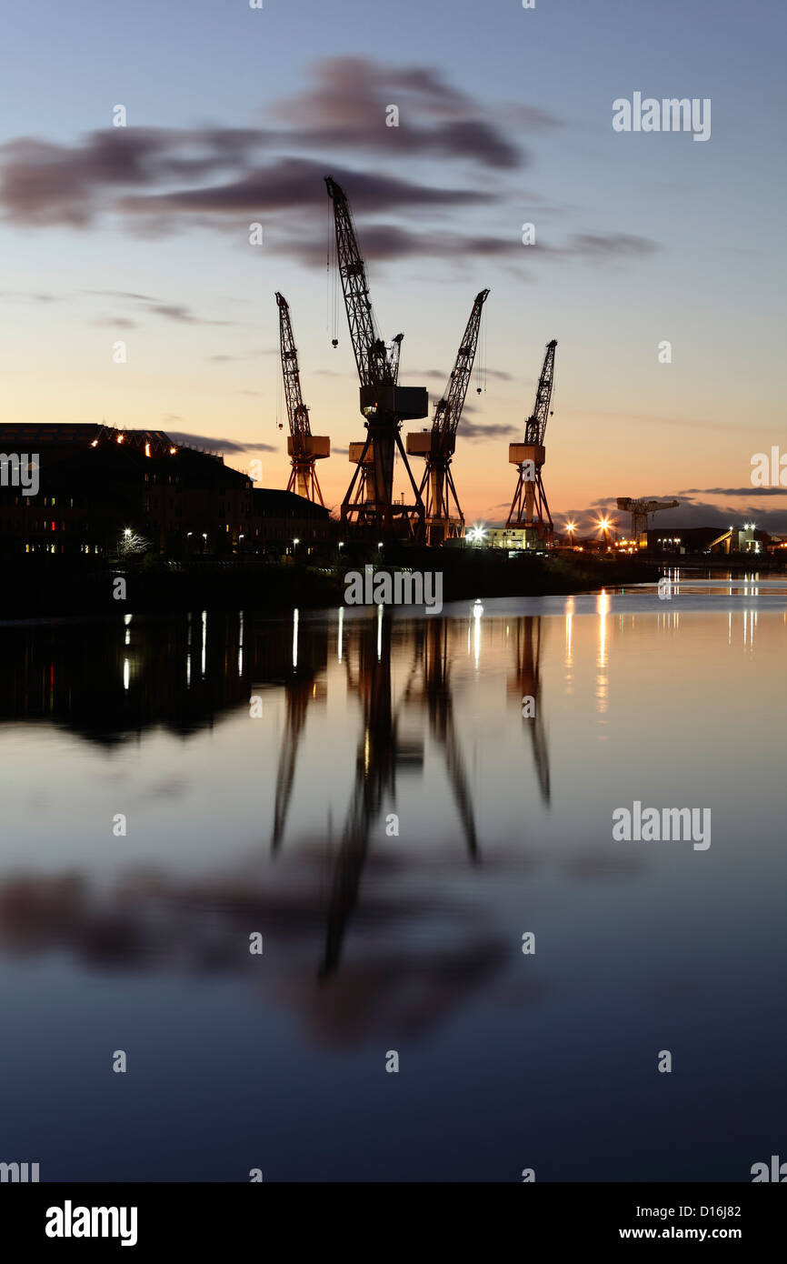 Sonnenuntergang über die Krane bei BAE Systems Werft neben dem Fluss Clyde in Govan, Glasgow, Schottland, Großbritannien Stockfoto