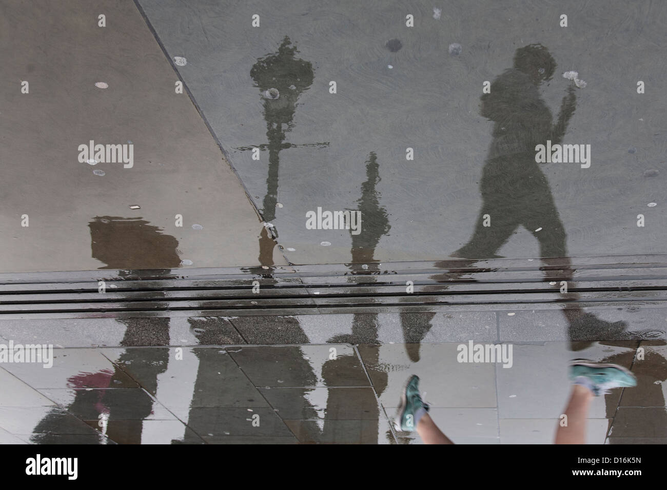 Reflexion in nassen Fahrbahn Frau laufen im Regen in Trafalgar square Stockfoto