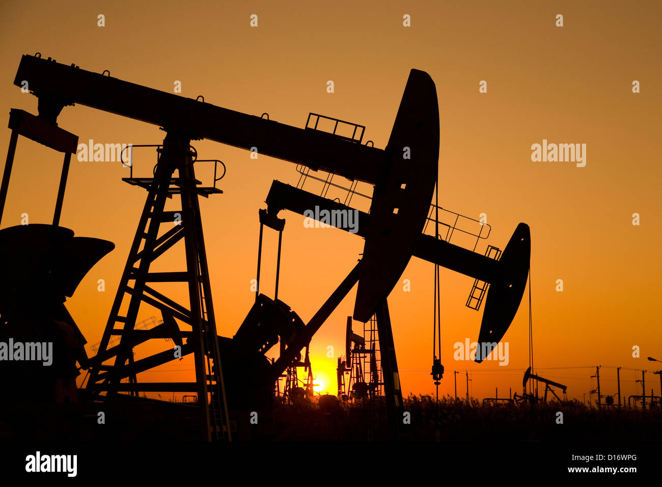 Silhouette der Ölquelle mit Sonnenaufgang Stockfoto