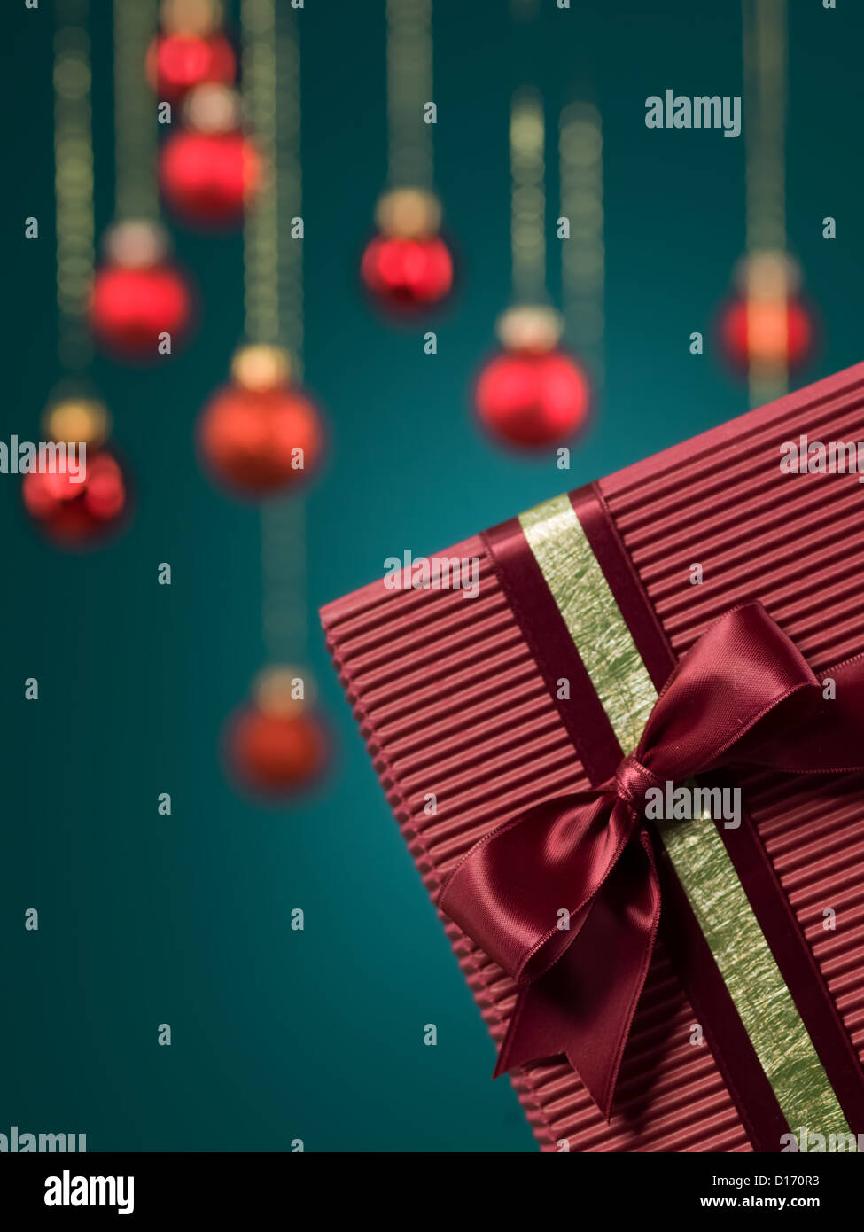 Nahaufnahme des einzigen Burgund Karton Geschenk-Box in der unteren rechten Ecke des Bildes mit roter Weihnachtsschmuck auf blauem Hintergrund gerahmt Stockfoto