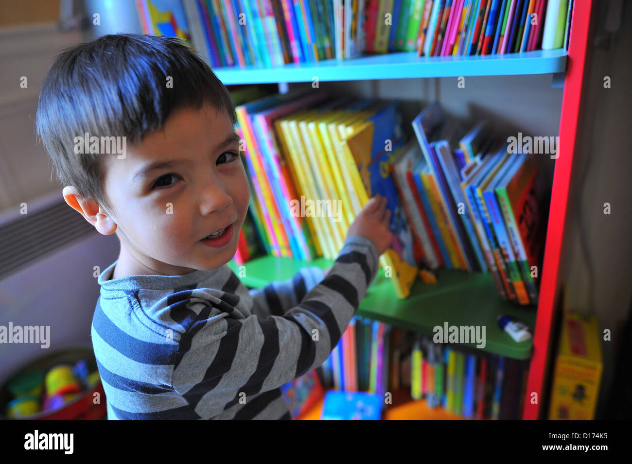 4-Year-Old Boy Kommissionierung ein Buch aus seiner Bibliothek Stockfoto