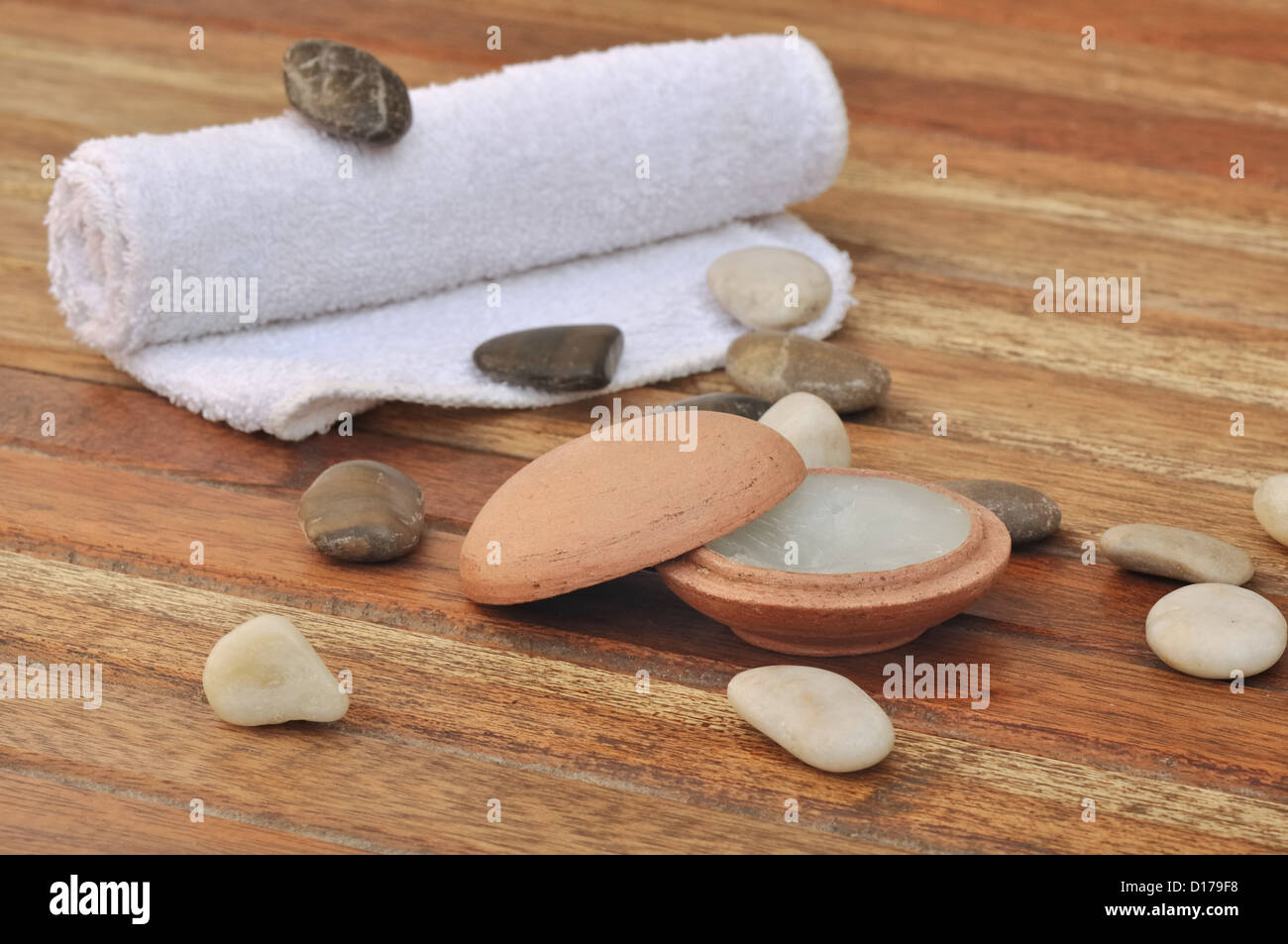 Massage Balsam in einem kleinen Tontopf mit Steinen und legte ein Handtuch auf die hölzernen Latten Stockfoto