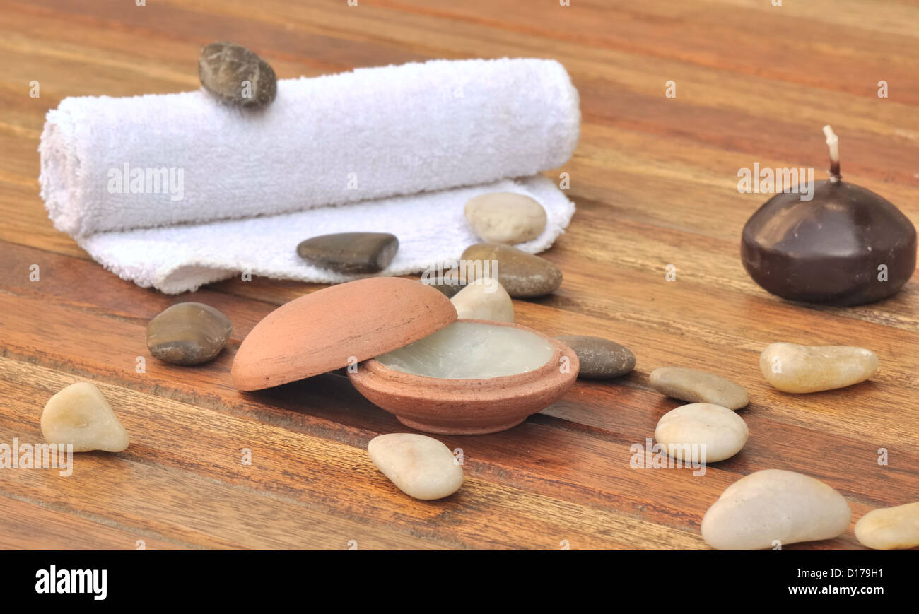 Massage Balsam in einem kleinen Tontopf mit Steinen und legte ein Handtuch auf die hölzernen Latten Stockfoto
