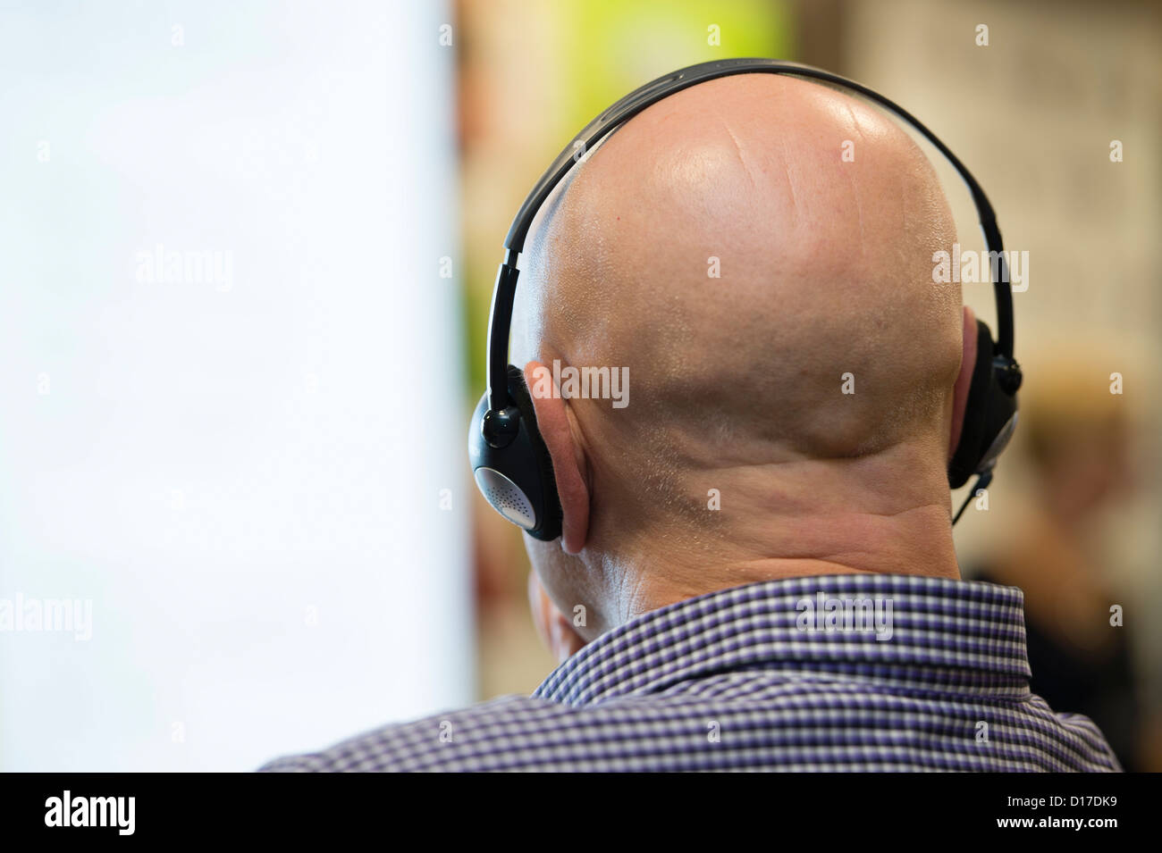 Rückansicht eines Mannes mit Simultanübersetzung Kopfhörer bei einem Treffen, Wales UK Stockfoto