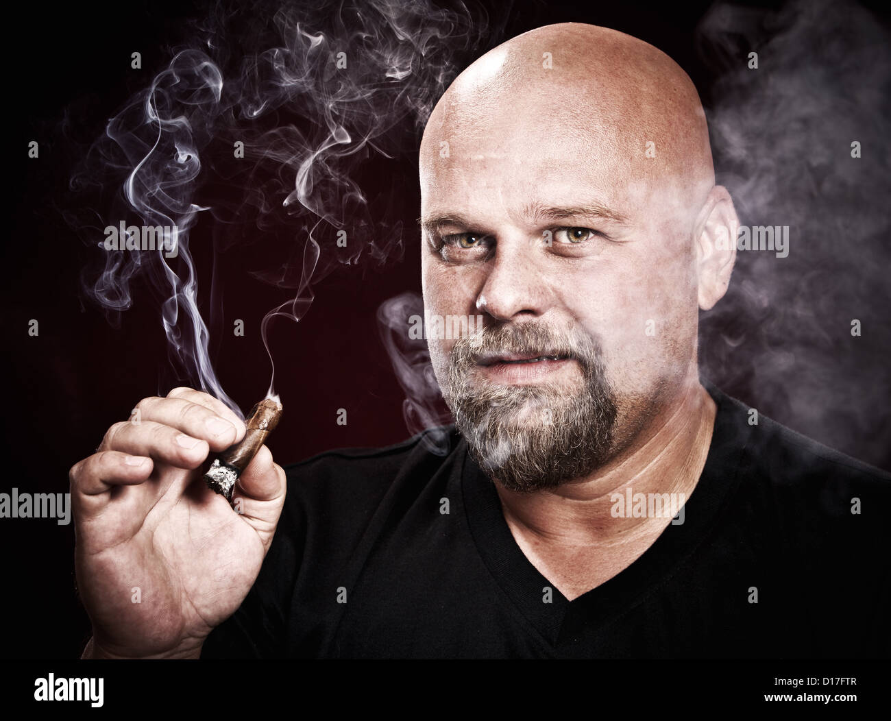 glatzköpfiger Mann mit einem Bart raucht eine Zigarre Stockfoto