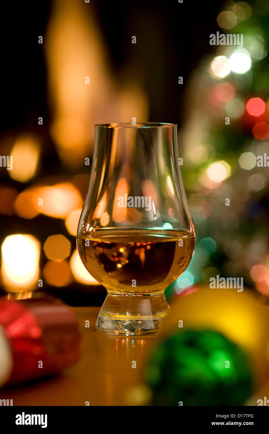 Glas Whisky zur weihnachtszeit mit bunten Kugeln und Baum Stockfoto