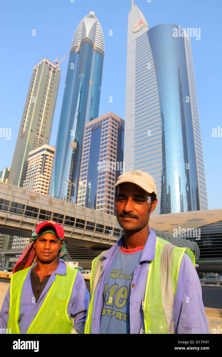 Dubai VAE, Vereinigte Arabische Emirate, Sheikh Zayed Road Asiatische Männer Wanderarbeiter, Immigranten Bangladeshi Hochhäuser Wolkenkratzer Gebäude Türme Stockfoto