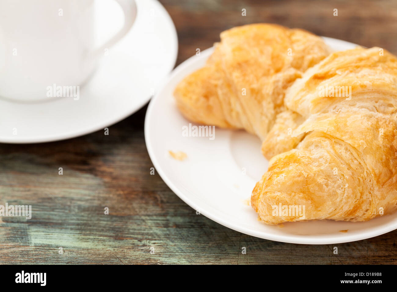 Croissant Brötchen mit Kaffee Espressotasse auf Grunge gemalt Holztisch, geringe Schärfentiefe Stockfoto