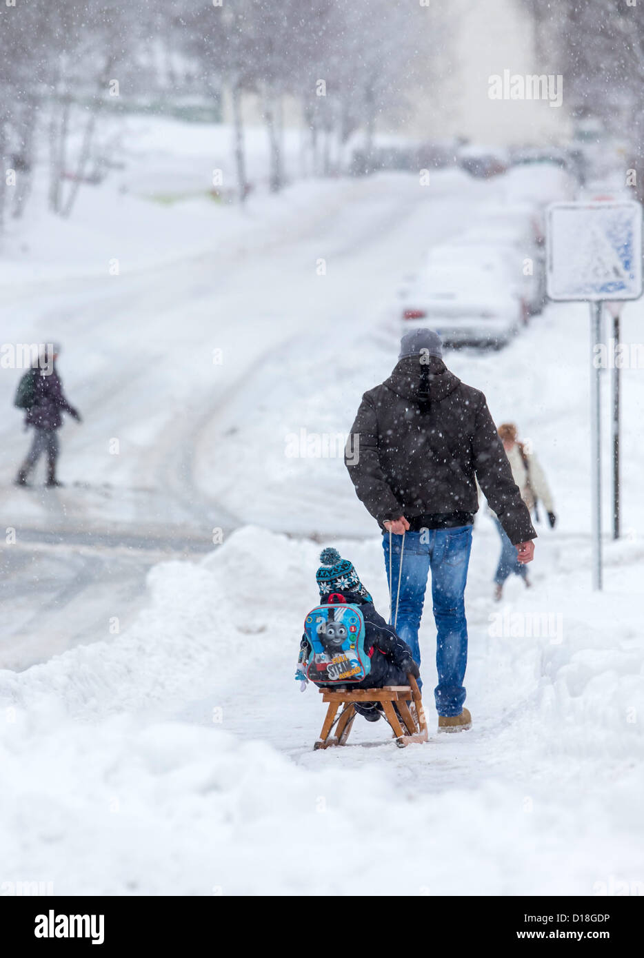 Vater zieht seinen Sohn auf einem Schlitten durch den Schnee in Ilmenau, Deutschland, 10. Dezember 2012. Starke Schneefälle verursachen weitere Probleme in der Arrea. Foto: Michael Reichel Stockfoto