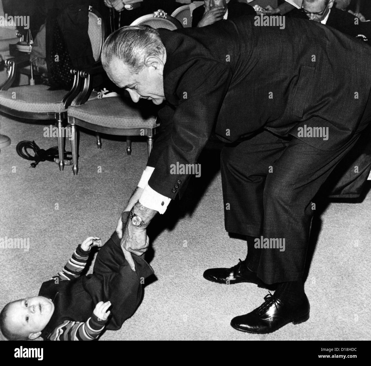 Präsident Lyndon Johnson zerrt die Beine seines Enkels Baby, Lyndon Patrick Nugent. Im Hintergrund ist das Publikum noch Stockfoto