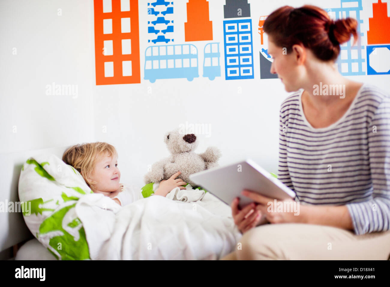 Mutter hält digital-Tablette, Tochter im Bett Stockfoto